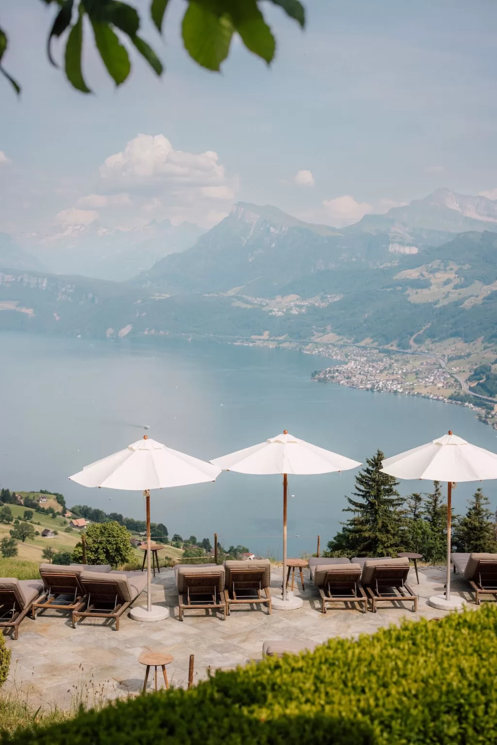 Row of sun loungers facing Lake Lucerne at Hotel Villa Honegg with parasols and alpine views.