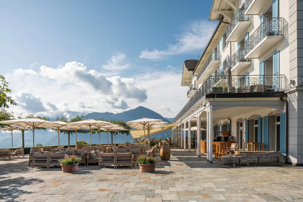 Spacious hotel terrace at Hotel Villa Honegg with parasols, comfy seating, and views of the Swiss Alps.