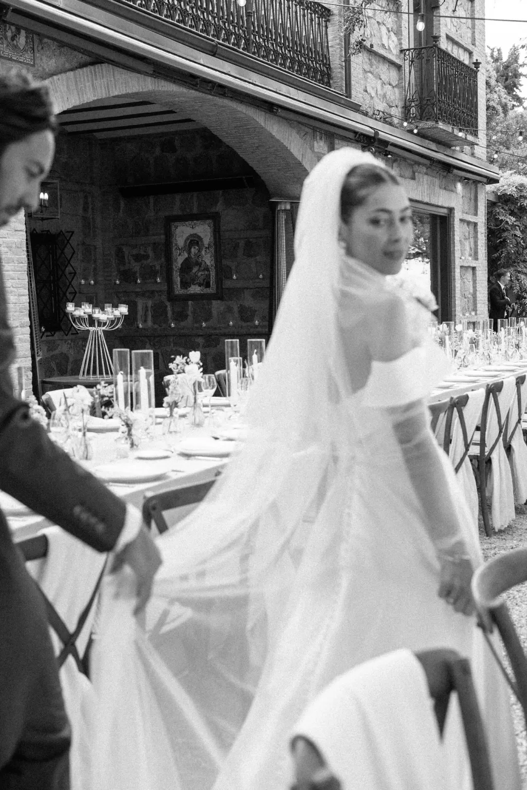 The bride walks through the elegant reception setup at Cigarral de la Mercedes, her groom holding her veil.
