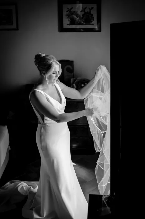 Black and white moment of the bride preparing her veil before the ceremony at Borgo Sant'Ambrogio.