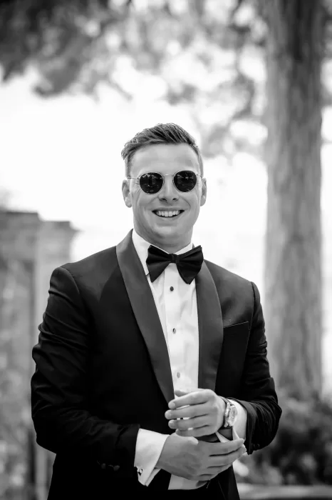 Groom in sunglasses and tuxedo smiling on the wedding day at Borgo Sant'Ambrogio.