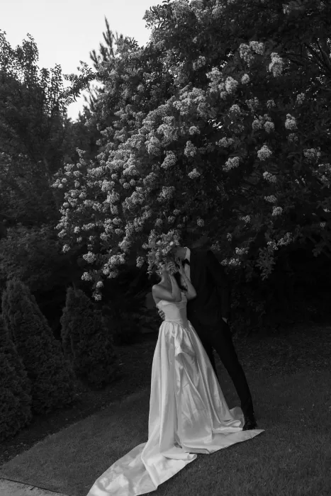 Romantic black and white photo of couple embracing under a blooming tree at The Bradford NC.