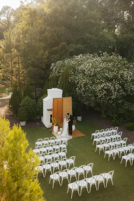 Aerial view of intimate outdoor wedding ceremony with white chairs at The Bradford NC.