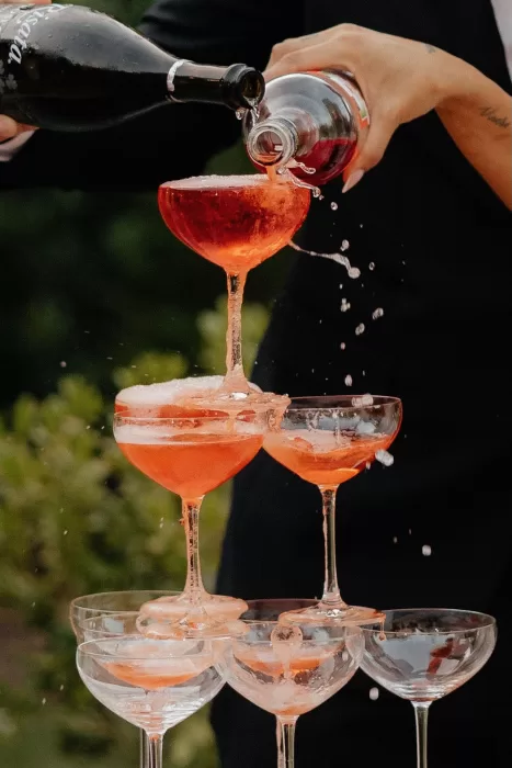 Tower of coupe glasses overflowing with rosé champagne at The Bradford NC wedding celebration.