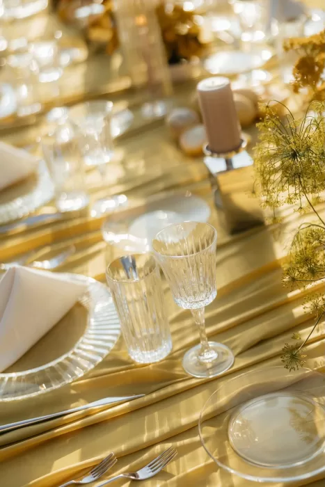 Elegant golden tablescape with glassware and neutral napkins at The Bradford NC, glowing in soft sunlight.