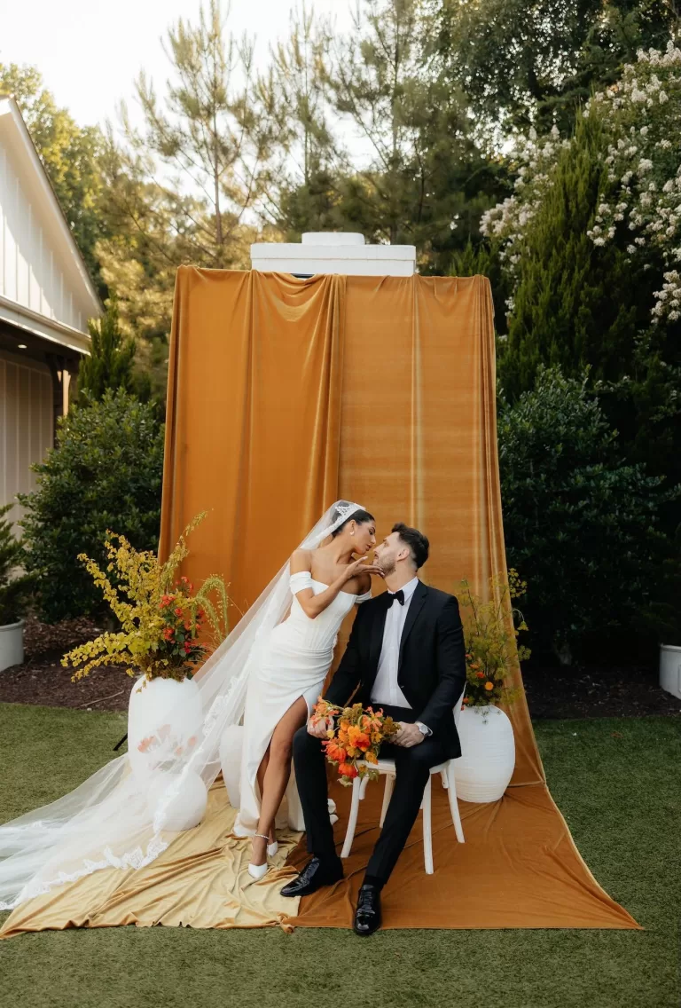 Bride and groom share a playful kiss while seated at their ceremony setup at The Bradford NC.