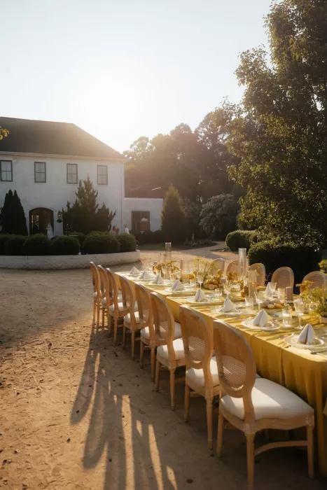 Elegant long yellow table setup in front of The Bradford NC, glowing in golden sunlight.