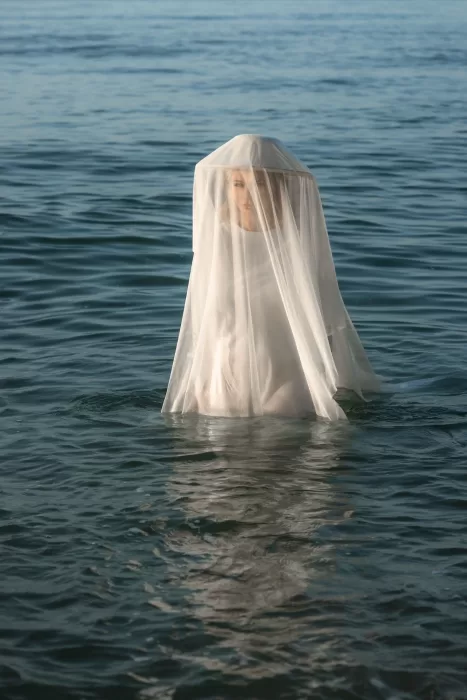 A dreamy image of the bride partially submerged in water, her veil billowing softly around her.