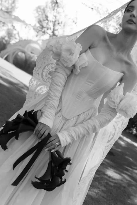 Bride seated on the lawn in lace-edged veil and romantic gown at Treelove Parkas, captured in timeless black and white.