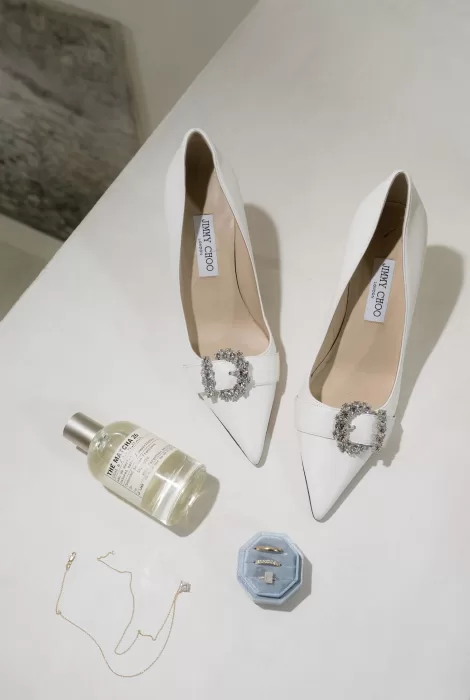 Bride’s accessories at Casa Olivi including Jimmy Choo heels, wedding rings, and perfume.