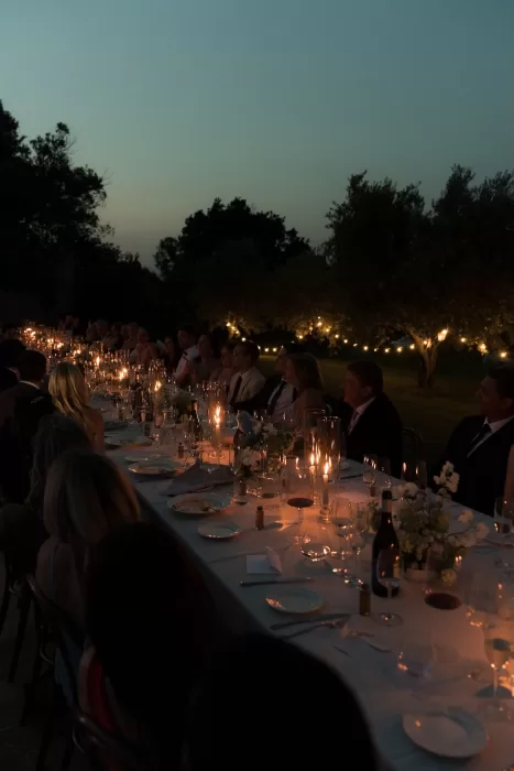 Guests enjoy a candlelit wedding dinner under the stars at Casa Olivi, surrounded by olive trees and glowing lights.