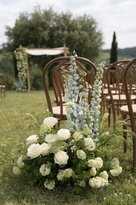 Soft ivory and blue floral arrangements line the ceremony aisle at Casa Olivi.