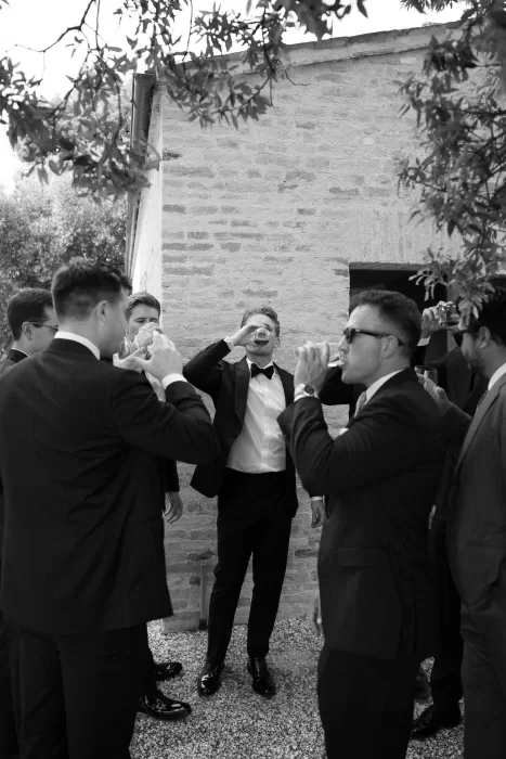 The groom and groomsmen share celebratory drinks outside the stone walls of Casa Olivi.