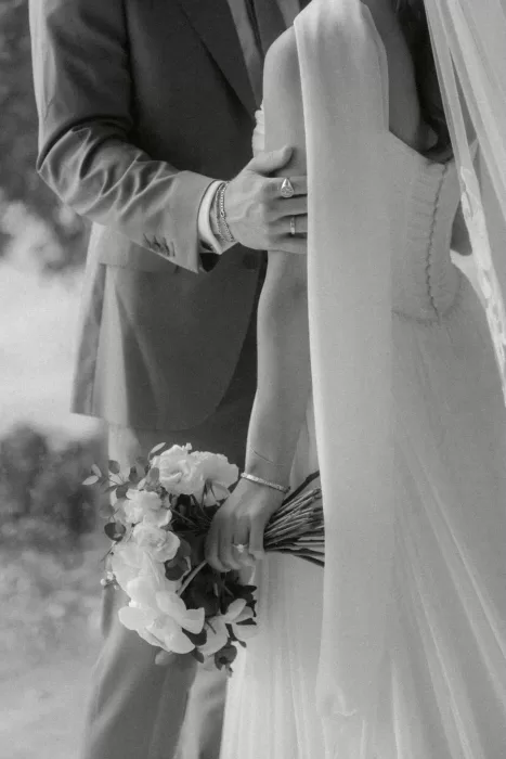 Intimate black-and-white close-up of the couple, focusing on the bride’s bouquet and elegant details.