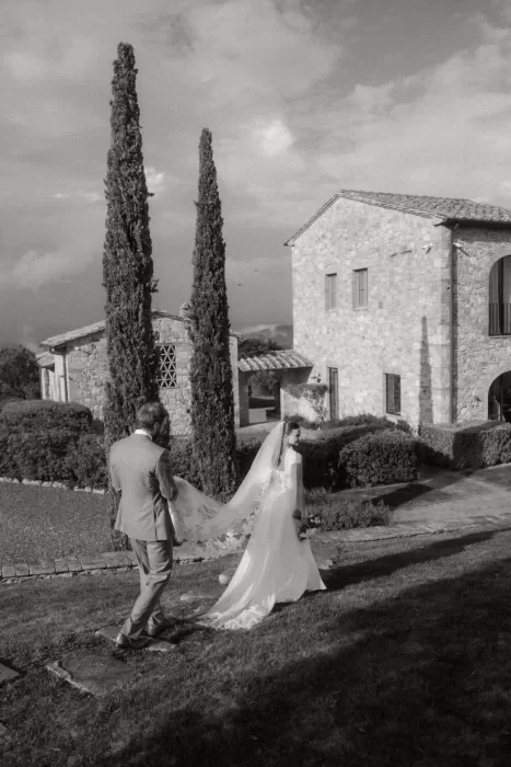 Groom tenderly holding bride beneath embroidered veil in an intimate moment at Castello di Casole.