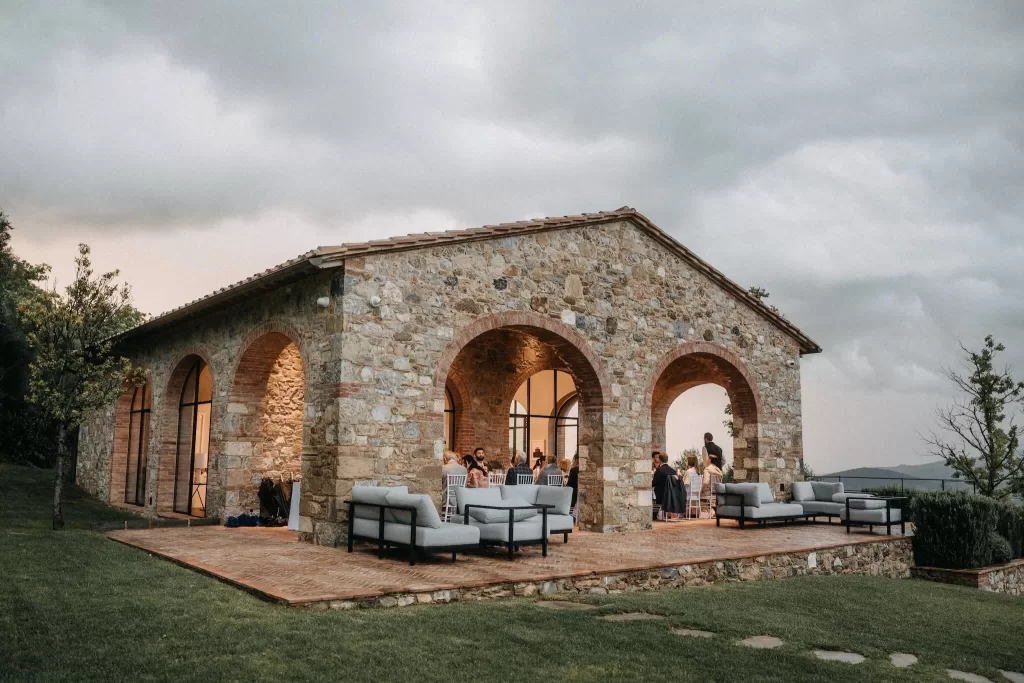Evening reception at Castello di Casole, with guests gathered in a stone building glowing with warm light.