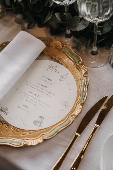 Close-up of the wedding menu on a gold-trimmed charger plate at Castello di Casole, featuring elegant Tuscan-inspired courses.