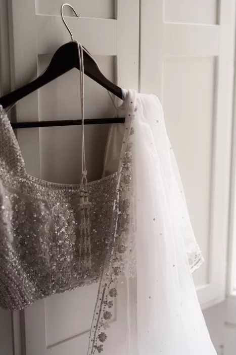 Beaded bridal lehenga and veil hanging beside soft window light at Castello di Montignano.