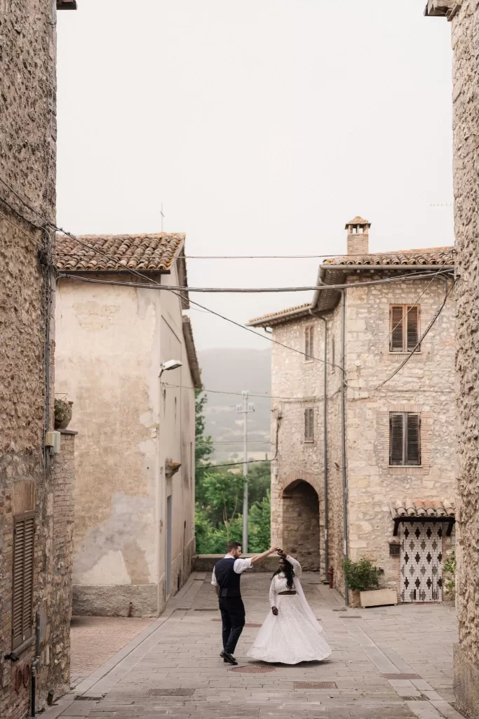 Bride and groom dancing in a quiet stone alley near Castello di Montignano
