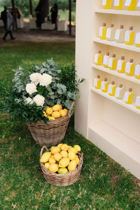 Baskets of lemons and white roses beside limoncello wedding favors at Castello di Montignano