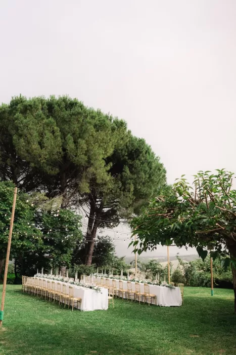 Long outdoor reception table under fairy lights surrounded by lush greenery at Castello di Montignano