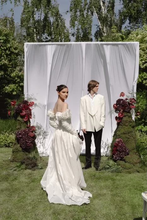 Groom awaits the bride beneath a white draped altar framed by sculptural flowers at Treelove Parkas.