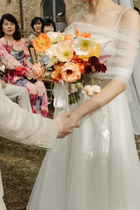 Bride holding a vibrant spring bouquet of poppies, tulips, and anemones at Conti di San Bonifacio.