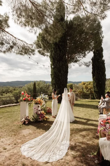 Wedding ceremony under tall cypress trees with panoramic Tuscan views at Conti di San Bonifacio.