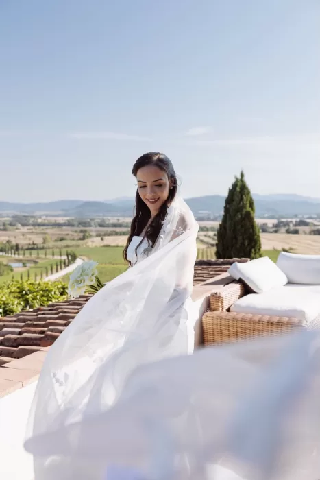 Bride with flowing veil standing on the terrace at Conti di San Bonifacio, overlooking the Tuscan countryside.