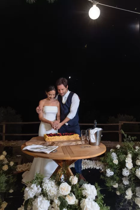 Bride and groom cutting their wedding cake under the stars at Conti di San Bonifacio, surrounded by florals.