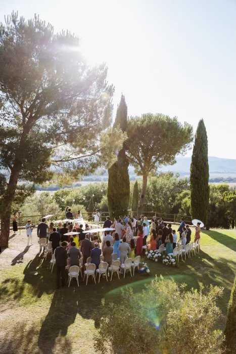 Aerial view of a summer ceremony under the Tuscan sun at Conti di San Bonifacio, surrounded by guests and cypress trees.
