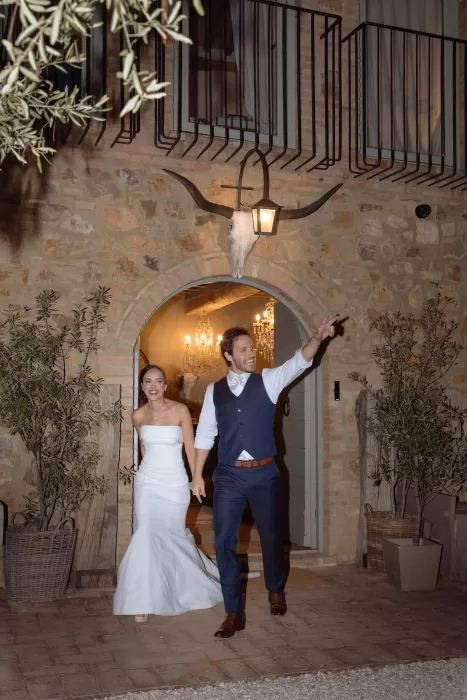 Newlyweds making a joyful evening entrance under the arch at Conti di San Bonifacio.