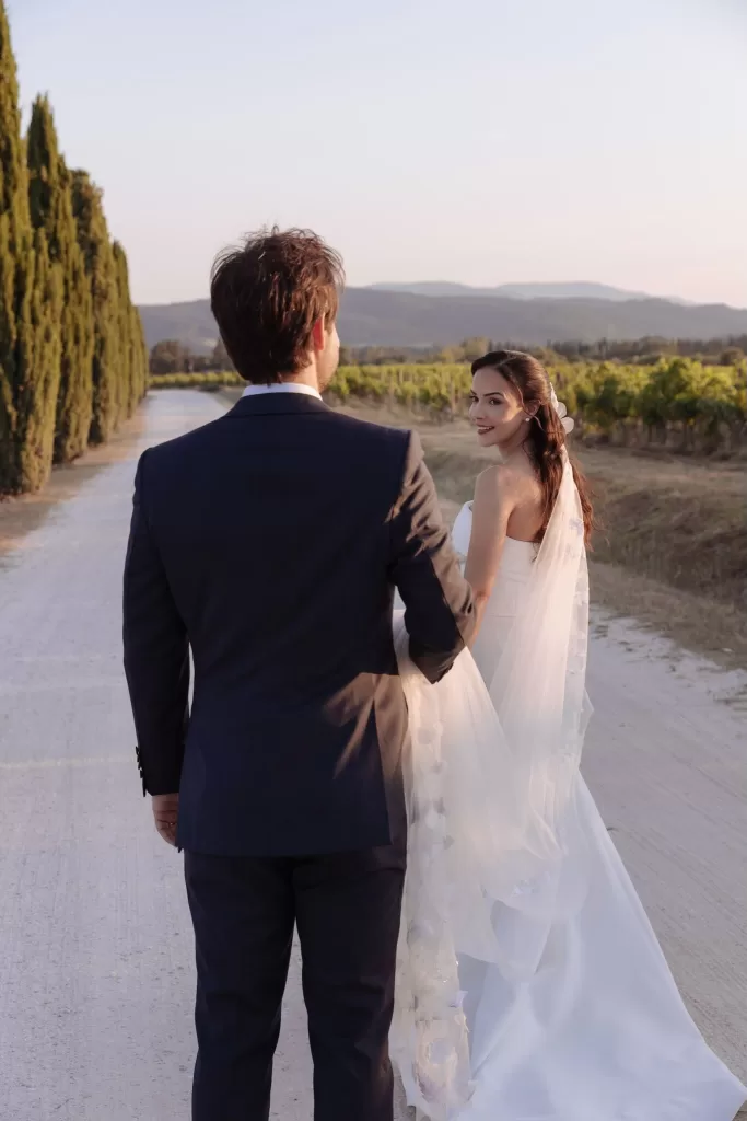 Bride and groom walking hand in hand along the cypress-lined path at Conti di San Bonifacio at golden hour.