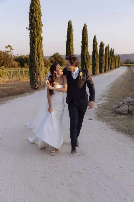 Bride and groom sharing a happy moment on the cypress-lined path at Conti di San Bonifacio.