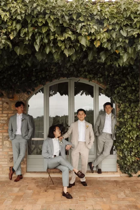Relaxed group of groomsmen in soft-toned suits outside a rustic villa at Conti di San Bonifacio.