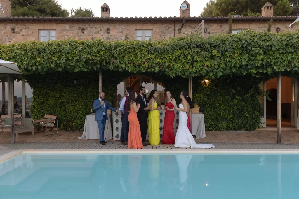 Wedding guests enjoying cocktail hour by the pool at Conti di San Bonifacio, with the villa wrapped in greenery.