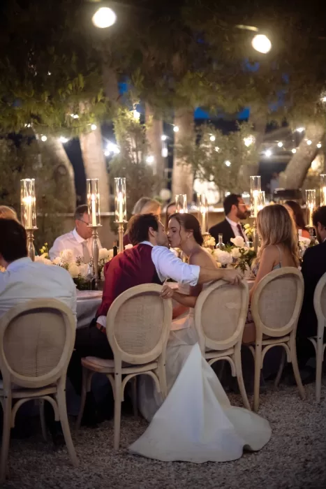 Bride and groom share a kiss at the candlelit reception table under the trees at Conti di San Bonifacio.