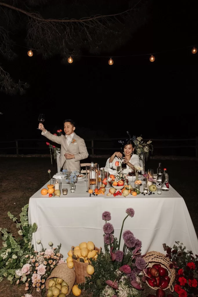 Bride and groom enjoying a vibrant sweetheart table under fairy lights at Conti di San Bonifacio.