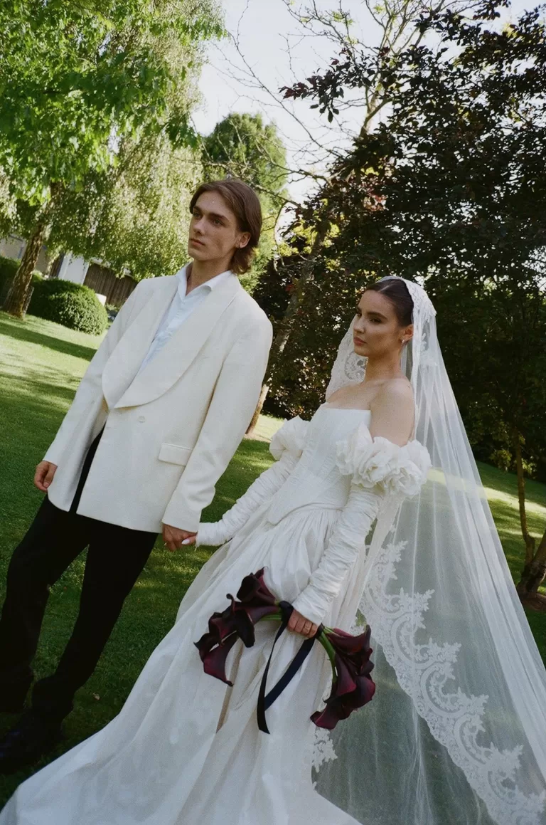 Bride and groom holding hands beneath the trees, her lace veil flowing at Treelove Parkas.