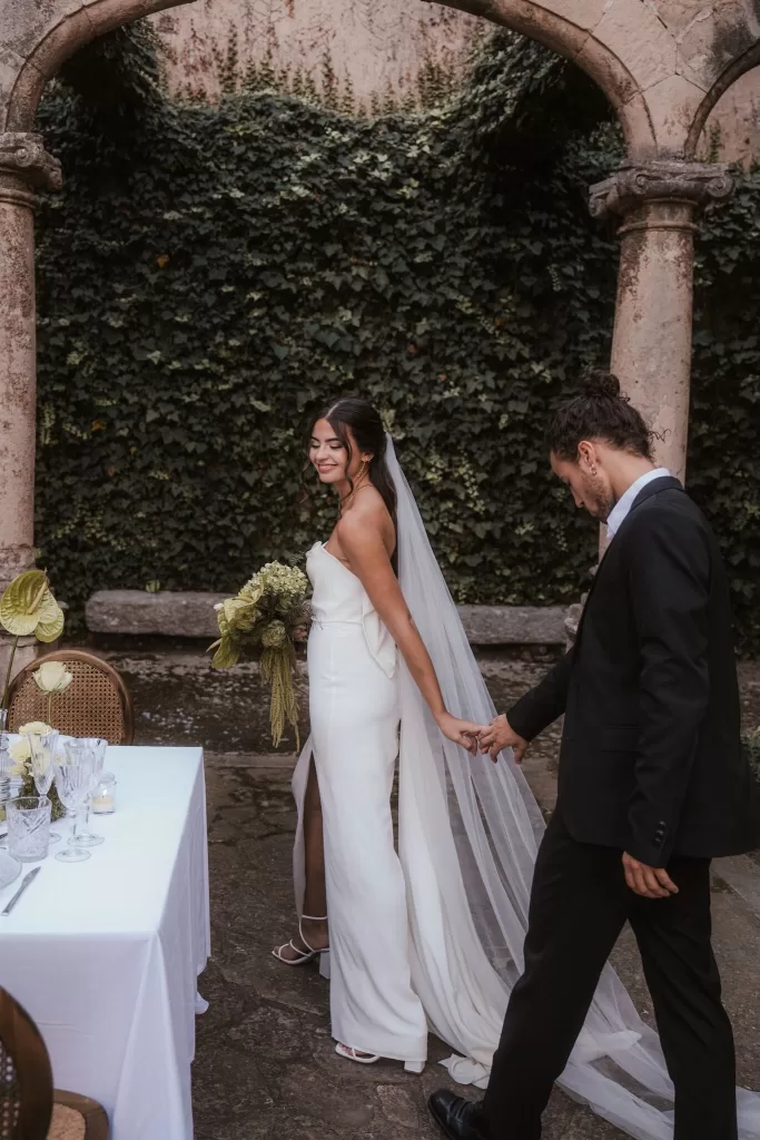 Bride and groom holding hands under ivy-covered arch at Finca Es Convent