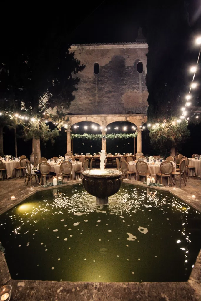 Nighttime courtyard with glowing fountain and string lights at Finca Es Convent