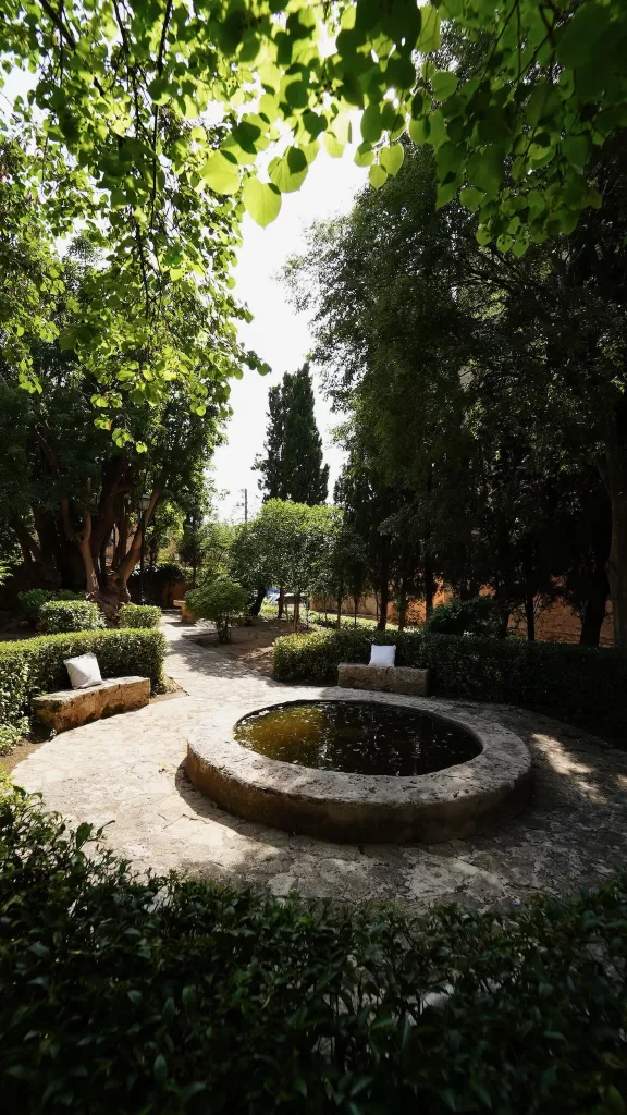 Tranquil garden corner with circular stone fountain and lush greenery at Finca Es Convent.