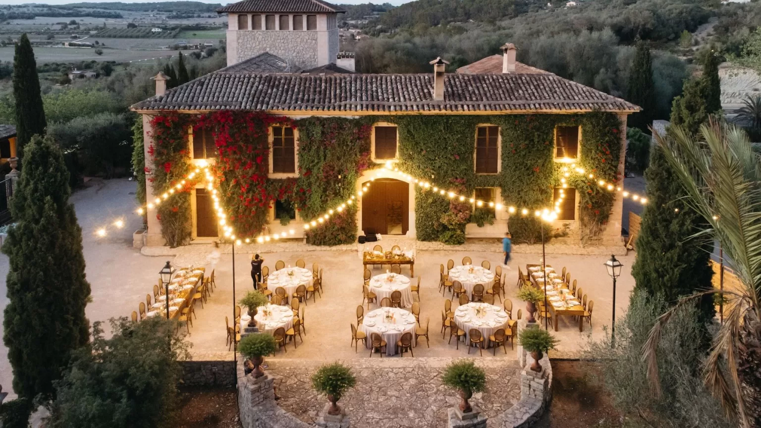 Aerial view of courtyard dinner setup at Finca Son Collell, surrounded by ivy-covered walls and festoon lights.