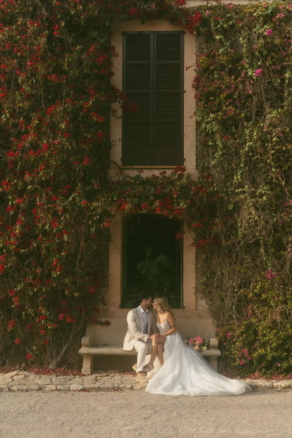 Couple sharing a quiet moment on a stone bench beneath blooming vines at Finca Son Collell