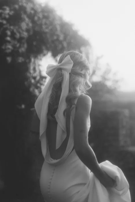 Soft black-and-white image of bride with long bow in her hair and an open-back dress at Finca Son Collell