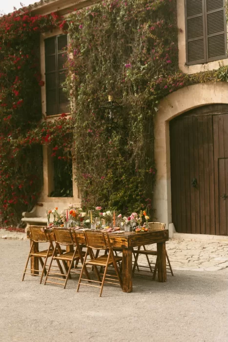 Long rustic table styled with bright blooms in front of ivy-covered building at Finca Son Collell