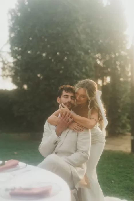 Bride embraces groom from behind in a dreamy garden setting at Finca Son Collell