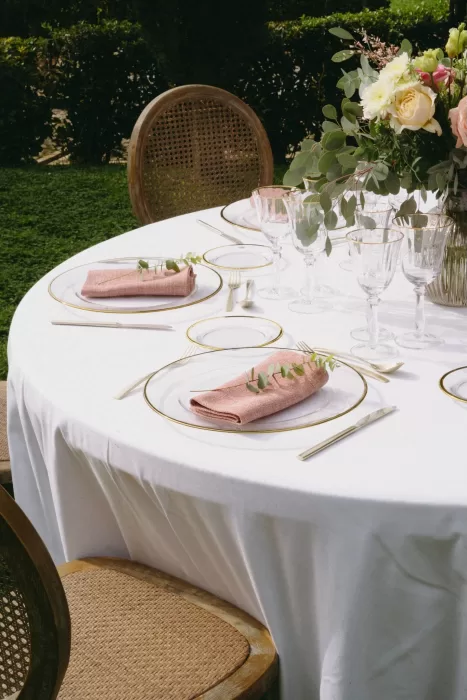 Elegant outdoor table set with gold-rimmed plates, pink napkins, and fresh florals at Finca Son Collell.