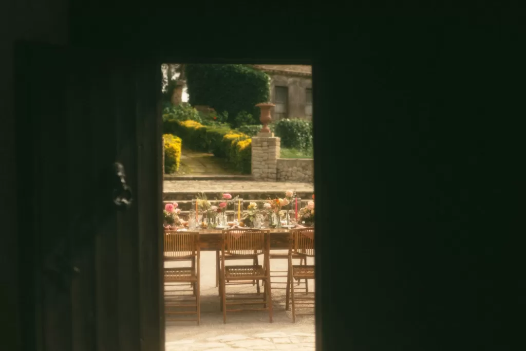 View through rustic door to outdoor wedding table decorated with colorful flowers at Finca Son Collell