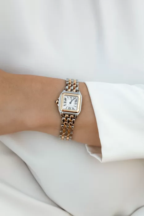 A close-up of the bride’s wrist adorned with a two-tone gold watch, captured against her minimalist white dress.